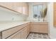 Bright laundry room features neutral toned cabinets, countertop, and decorative patterned tile flooring at 9781 E Gamble Ln, Scottsdale, AZ 85262