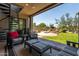 A covered outdoor patio with elegant seating and spiral staircase overlooking a lush green lawn and desert landscape at 9781 E Gamble Ln, Scottsdale, AZ 85262