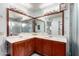 Well-lit bathroom showcasing double sinks with a large mirror, a vanity, and a glass-enclosed shower at 10216 W Minnezona Ave, Phoenix, AZ 85037