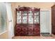 Ornate dining cabinet with glass shelving, detailed wood carvings, and adjacent outdoor access at 10216 W Minnezona Ave, Phoenix, AZ 85037