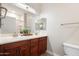 Bathroom featuring double sinks, wooden cabinets, large mirror, and ample lighting at 10757 N 74Th St # 2003, Scottsdale, AZ 85260