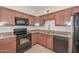 Well-equipped kitchen with ample wooden cabinetry, black appliances, granite countertops, and tile backsplash at 11388 N 114Th Dr, Youngtown, AZ 85363