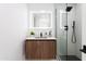 Modern bathroom featuring a wood vanity, white countertops, and a sleek glass-enclosed shower with black fixtures at 11601 N 64Th Pl, Scottsdale, AZ 85254