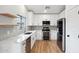 Bright kitchen with white cabinetry, modern appliances, marble counters, and light wood flooring at 13326 W Watson Ln, Surprise, AZ 85379