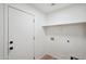 Clean, well-lit laundry room features new fixtures, a shelf and crisp, white paint at 13326 W Watson Ln, Surprise, AZ 85379