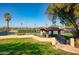 Outdoor tennis courts with a shaded seating area surrounded by lush green grass and trees at 1349 E Anasazi St, Mesa, AZ 85203