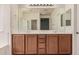 Bathroom featuring a double sink vanity with wood cabinets, a large mirror, and neutral walls at 1481 E Lark St, Gilbert, AZ 85297