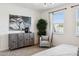 Bright bedroom with large dresser, art, chair, and natural lighting from large window at 1503 S 239Th Dr, Buckeye, AZ 85326