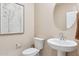 Neutral-toned powder room showcasing a pedestal sink, round mirror, and framed botanical art at 1531 S 239Th Dr, Buckeye, AZ 85326