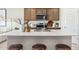 Modern kitchen island featuring a quartz countertop, stainless steel sink, and stylish bar stool seating at 1531 S 239Th Dr, Buckeye, AZ 85326