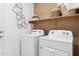 Bright laundry room with modern washer and dryer, complemented by stylish decor on the shelf at 1531 S 239Th Dr, Buckeye, AZ 85326