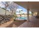 Relaxing covered patio overlooking a sparkling pool with lush landscaping and blue skies at 15602 N 19Th St, Phoenix, AZ 85022