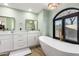 Bright bathroom featuring double sinks, quartz counters, vanity and a soaking tub beneath a picture window at 15747 E Greystone Dr, Fountain Hills, AZ 85268