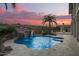 Inviting pool area with a waterfall feature, lush landscaping, and a beautiful sunset backdrop at 15747 E Greystone Dr, Fountain Hills, AZ 85268