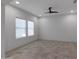 Minimalist bedroom featuring neutral walls, a ceiling fan, and abundant natural light through two large windows at 17530 W Oberlin Way, Surprise, AZ 85387