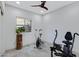 Bright exercise room featuring tiled floors, a ceiling fan, and a large window overlooking the backyard at 17530 W Oberlin Way, Surprise, AZ 85387