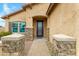 Close-up of home's entrance featuring a black security door, stone pillars, and a paved walkway at 17530 W Oberlin Way, Surprise, AZ 85387