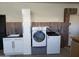 Functional laundry room with white cabinets, utility sink, modern washer and dryer, and accent wall at 17530 W Oberlin Way, Surprise, AZ 85387