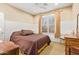 Cozy bedroom featuring wainscoting, a ceiling fan, and a window with plantation shutters at 17846 W Fairview St, Goodyear, AZ 85338