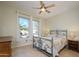 Bright bedroom featuring tile floors, a ceiling fan, and two sunny windows offering a neighborhood view at 18701 N Diamond Dr, Surprise, AZ 85374