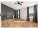 Spacious bedroom with modern accent wall, wood flooring, a ceiling fan, and ample natural light from multiple windows at 19409 N 45Th Dr, Glendale, AZ 85308