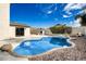 Sparkling pool surrounded by rock landscaping, with a view of the backyard and an outdoor fireplace at 19409 N 45Th Dr, Glendale, AZ 85308