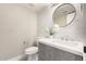 Stylish powder room featuring a gray vanity with white countertop and decorative tile backsplash and round mirror at 19409 N 45Th Dr, Glendale, AZ 85308