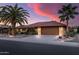 Charming house with desert landscaping and mature palm trees under a dramatic sunset and a spacious driveway at 20639 N 123Rd Dr, Sun City West, AZ 85375