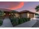 Inviting home entrance with tiled roof, iron gate, lush landscaping, and a charming desert aesthetic at dusk at 20639 N 123Rd Dr, Sun City West, AZ 85375