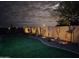 Inviting backyard at night with artificial turf, desert landscaping, and a privacy wall adorned with decorative accents at 24847 N 175Th Dr, Surprise, AZ 85387