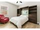 Stylish bedroom with a murphy bed, built-in shelving, and a comfortable red armchair at 24847 N 175Th Dr, Surprise, AZ 85387