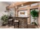 Stylish home bar area with stone accents, comfortable seating, and well-lit display shelving at 3603 E Indigo Bay Ct, Gilbert, AZ 85234