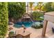 An outdoor pool area featuring a rock waterfall, lush greenery, and a built-in grill at 3603 E Indigo Bay Ct, Gilbert, AZ 85234