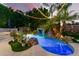 A luxurious swimming pool with a rock waterfall feature and ambient lighting at dusk at 3603 E Indigo Bay Ct, Gilbert, AZ 85234