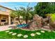 Beautiful pool with a rock waterfall feature, lush landscaping, and grass pavers at 3603 E Indigo Bay Ct, Gilbert, AZ 85234