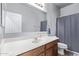 A well-lit bathroom featuring a single sink, a large mirror, and a shower-tub combination with a gray shower curtain at 38208 N La Grange Ln, San Tan Valley, AZ 85140