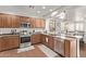 Well-lit kitchen boasts stainless steel appliances, plenty of counter space, and wood cabinets at 38208 N La Grange Ln, San Tan Valley, AZ 85140