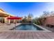 An inviting pool with a red umbrella and desert landscaping perfect for outdoor living at 38208 N La Grange Ln, San Tan Valley, AZ 85140