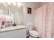 Bright bathroom featuring a vanity with a granite countertop, toilet, mirror and a decorative pink shower curtain at 4226 E Spawn Ln, Gilbert, AZ 85296