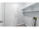 A clean laundry room featuring a white door, shelving, and washer hookups at 5145 W Tonto Rd, Glendale, AZ 85308