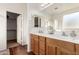 Bright bathroom with double sinks, wooden cabinets, and a separate room for the toilet at 6009 W Questa Dr, Glendale, AZ 85310