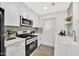 Well-lit kitchen showcasing stainless steel appliances, modern white cabinets, and a breakfast bar with wood-look flooring at 601 W Yukon Dr # 1, Phoenix, AZ 85027