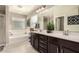 Elegant bathroom featuring dual sinks, dark cabinets, a soaking tub, and tiled floors at 7337 S Debra Dr, Gilbert, AZ 85298