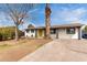 A charming single-story home features a yellow door and mature trees in the front yard at 7458 E Clovis Cir, Mesa, AZ 85208