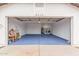 View of the open garage featuring bright blue flooring and white walls, including laundry and storage at 8826 W Amelia Ave, Phoenix, AZ 85037