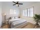 Staged bedroom featuring wood floors, light walls, ceiling fan, window, and neutral-toned bedding at 10243 N 103Rd St, Scottsdale, AZ 85258