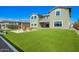 Spacious backyard featuring artificial turf, a built-in grill, and a modern fire pit area at 10635 E Tesla Ave, Mesa, AZ 85212