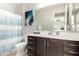 Bright bathroom featuring a modern vanity with dark wood cabinets and a shower with a blue striped curtain at 10635 E Tesla Ave, Mesa, AZ 85212