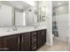 Bathroom featuring double sinks, dark wood cabinetry, and a shower/tub combination with a tiled backsplash at 10635 E Tesla Ave, Mesa, AZ 85212