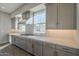 Modern kitchen featuring gray cabinetry, white countertops, stainless steel range hood, and stylish tile backsplash at 10972 N Hershey St, Surprise, AZ 85388